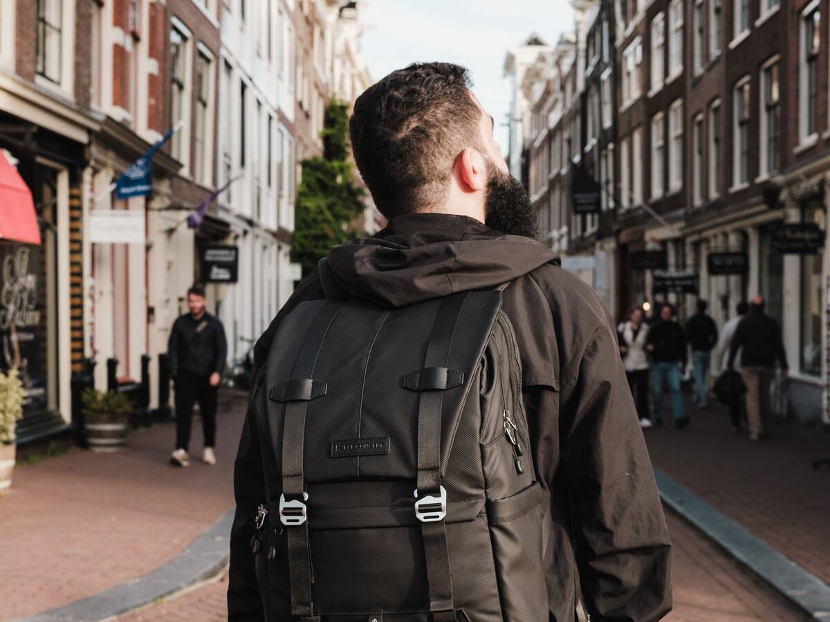 A traveller in Amsterdam looking up at the gabled houses on a brick street