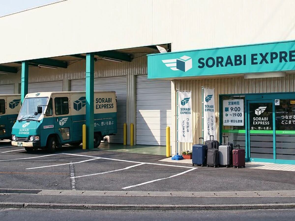 Koffers op een rij voor een bagagedepot, met twee bestelwagens in de laadzones